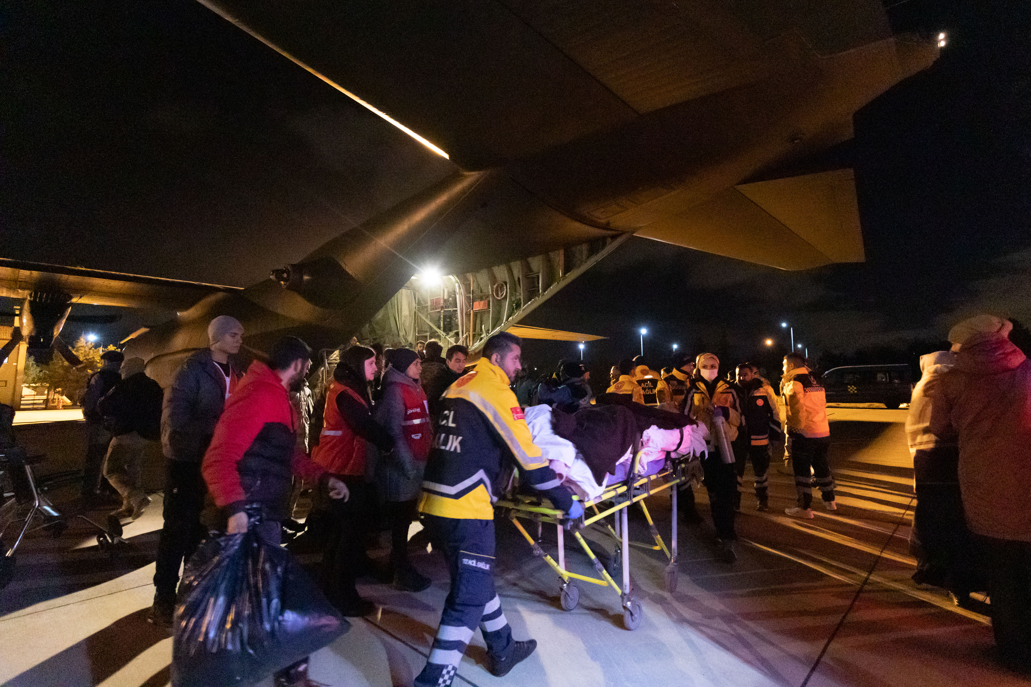 Image shows RAF medics attending patient on the airfield by RAF Hercules aircraft.